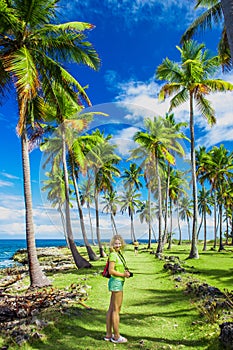 Young girl traveller on the green road with palm trees.