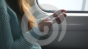 Young girl travelling in a train and using mobile phone. Beautiful woman sends a message from the smartphone. Attractive