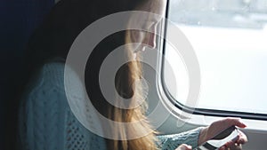 Young girl travelling in a train and using mobile phone. Beautiful woman sends a message from the smartphone. Attractive