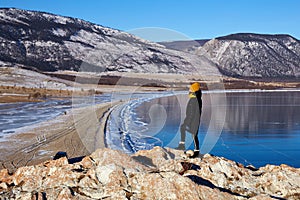 A young girl travels on Lake Baikal in winter. Beautiful winter mountain landscape, transparent ice