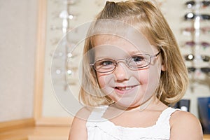 Young girl trying on eyeglasses at optometrists