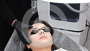 A young girl undergoes laser removal of permanent makeup in a beauty salon. Correction of eyebrows