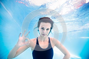 Young girl underwater showing ok sign