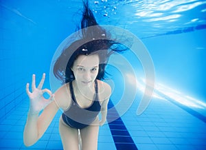 Young girl underwater showing ok sign