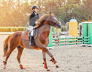 Young girl in uniform jumping with sorrel horse.