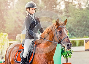 Young girl in uniform jumping with sorrel horse.