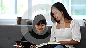 Young girl using digital tablet doing homework online during extra curricular classes with her tutor. photo