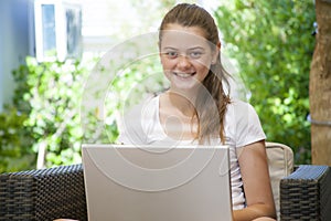 A young girl using her laptop outside