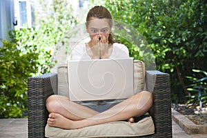 A young girl using her laptop outside