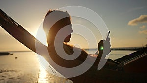 Young Girl Using Mobile Phone in Hammock Silhuette Against Beautiful Sunset at the Beach. Koh Phangan, Thailand. HD