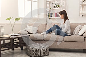 Young girl using mobile phone on sofa