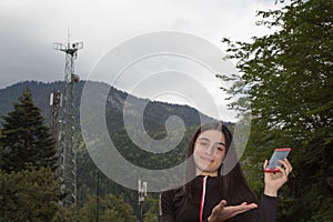 Young girl using mobile phone with Telecommunication towers with TV antennas and satellite dish. The concept of communication tech