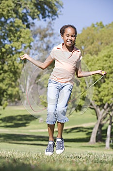 Young girl using skipping rope outdoors smiling photo