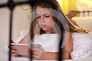 Young girl using smartphone in bed