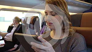 Young girl using tablet, serfing internet. Passenger in train