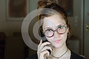 A young girl using a wireless phone at home, looking serious.