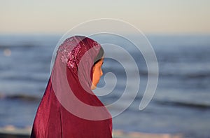Young girl with veil on head waiting by the sea