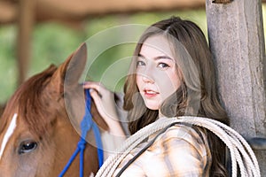 A young girl in a village stables saddles her horse. Beautiful girl taking care of stallion. Female and beautiful horse