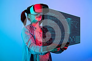 Young girl with a VR headset on the head looking at a futuristic screen in fron of her