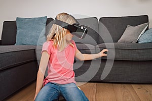 Young girl in VR headset touching air during virtual reality experience