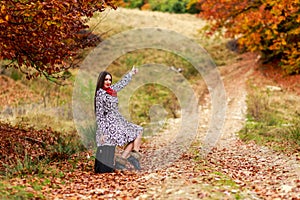 Young girl waiting on a country road with her suitcase.