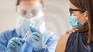 Young girl is waiting for her vaccination dose against coronavirus to be applied by a medical worker