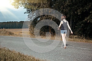 Young girl walking barefoot on the road, the concept of summer and travel