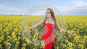 Young girl walking through canola field facing camera