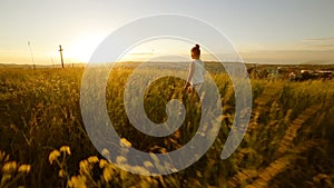 Young girl walking on the field to cross on sunset