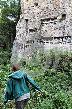 young girl walking in the jungle to visit funerary tau tau effigies and cave cemetery in tana toraja, sulawesi