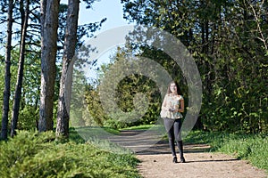 Young girl walking in spring forest with camera and taking pictures