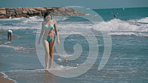 Young Girl Walks along the Beach of the Sea Coast in Slow Motion