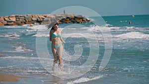 Young Girl Walks along the Beach of the Sea Coast in Slow Motion