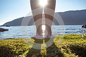 A young girl walks barefoot on the beach. Girl`s legs in the water in the sunlight.