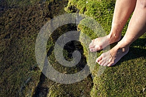 A young girl walks barefoot on the beach. Girl`s legs in the water in the sunlight.