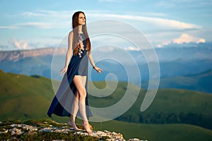 A young girl walks on top of a mountain, against the backdrop of Caucasian ridge