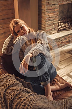 Young girl in warm knitted sweater at home. Cozy style