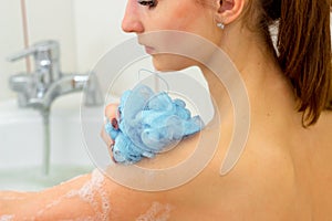 Young girl washes in the bathroom with a blue washcloth in hand