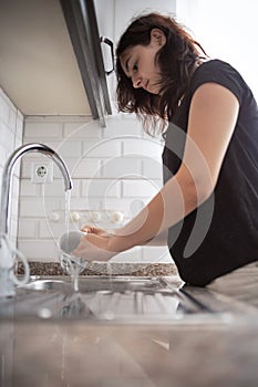 Young girl is washing dishes. The teenager helps with home routine