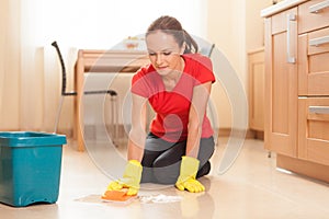 Young girl washing floor in kitchen.