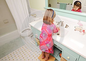 Young girl washing hands in bathroom