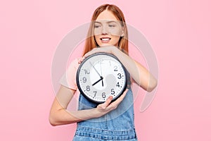 Young girl with a watch in her hands, on an isolated pink background