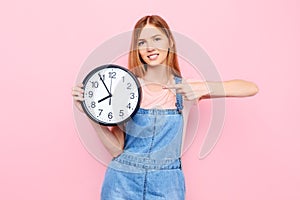 Young girl with a watch in her hands, on an isolated pink background