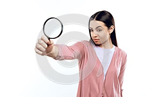 Young girl watches through magnifying glass.