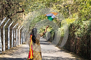 young girl waving the indian tricolor national flag at remote location at day from back angle
