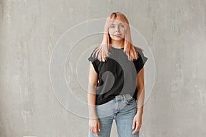 Young girl wearing blank black t-shirt. Concrete wall background. Horizontal