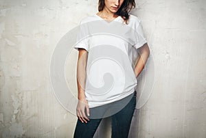 Young girl wearing blank t-shirt and black jeans. Concrete wall background