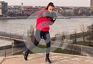 Young girl wearing boxing gloves throwing a punch - martial arts