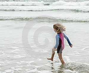 Young girl wearing a colorful swimming suit having fun splashing at the beach