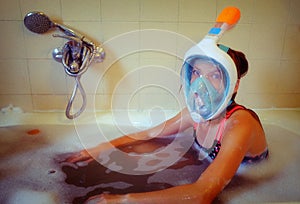 Young girl wearing a full face snorkelling mask sitting in the b photo